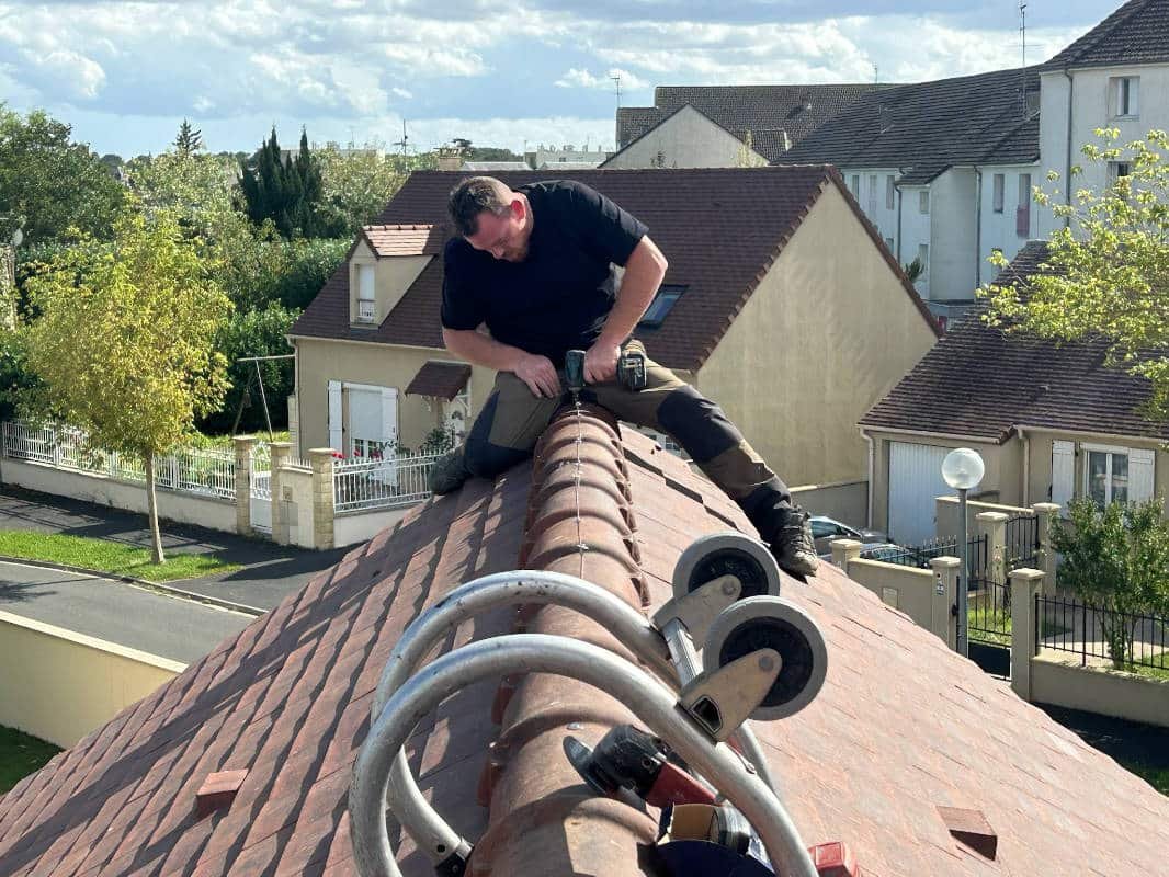Jean Paul Robert entrain de fixer un faîtage sur une toiture